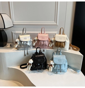 Close-up of stylish wrinkled leather mini backpacks with cute teddy bear pendants in five colors