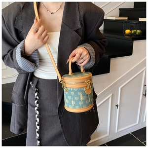 Chic blue denim bucket bag with vintage gold patterns and brown leather trims details