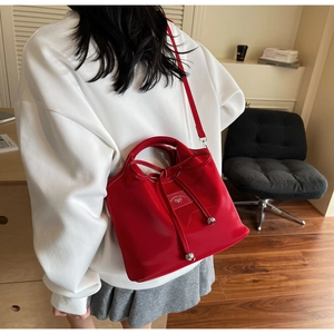 Detail view of red glossy leather handbag with bow tie and adjustable shoulder strap