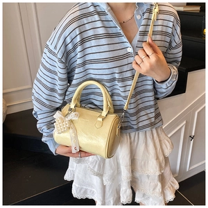Détail d'un sac cylindrique jaune avec breloque nœud en dentelle sur un mannequin