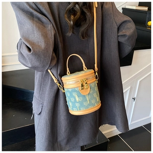 Detail view of denim bucket bag with heart patterns and tan leather trim on wood stairs