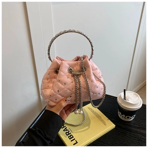 Pink quilted bucket bag with rhinestone details and metal ring handle in a cafe setting