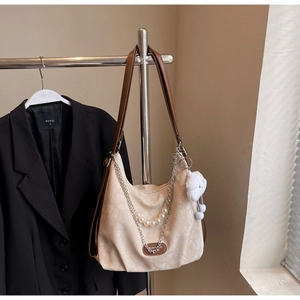 Close-up of beige jacquard tote bag with pearl chain detail and plush cloud charm