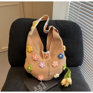 Detail of hand-crocheted shoulder bag with colorful 3D flower motifs and knit texture