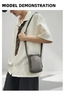 Detail of grey crinkled nylon crossbody bag with dual zipper pockets and neon green accents