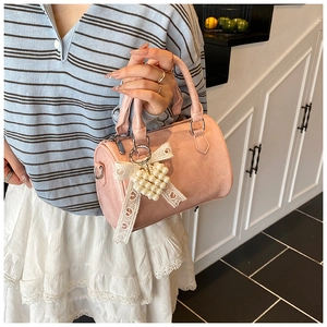 Détail d'un sac Boston rose avec charme de perles en cœur et nœud en dentelle élégant