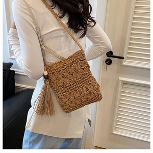 Detail of handmade straw shoulder bag with crochet floral pattern and beaded tassels