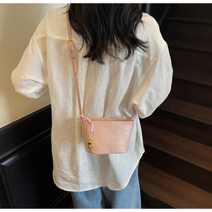 Chic pink crocodile pattern bucket bag with a gold skull charm shown on a model