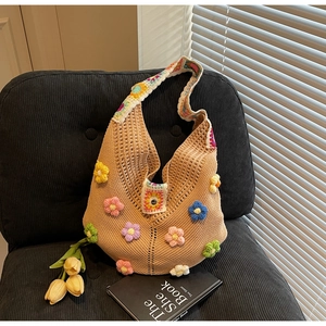 Macro detail of 3D crochet flowers and wide jacquard strap on a knit beach bag