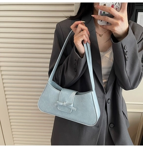 Light blue underarm bag with pleated texture and bow detail shown on a female model