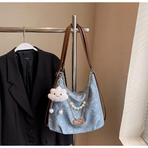 Detail of floral canvas hobo bag with pearl chain, leather strap, and cloud charm
