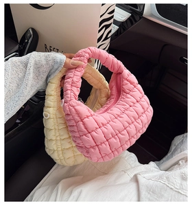 Detail view of quilted puffer cloud bags in pastel pink and soft cream yellow nylon
