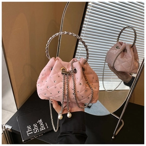 Close-up of pink quilted bucket bag with rhinestones, metal handle and pearl charm detail