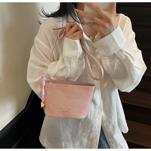 Detail of pink crocodile pattern bucket bag with golden brand logo and metal charm