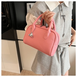 Detail of pink lychee grain Boston bag with cute silver whale charm and round handles