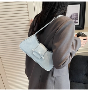 Detail of light blue faux leather shoulder bag featuring a chic bow and crackle texture
