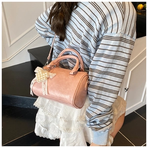 Sac cylindre brillant rose avec un charmant nœud en dentelle et perles sur un escalier