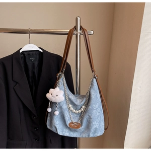 Detail view of a floral hobo bag with leather straps and cloud charm on a hanger