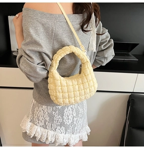 Detail of light yellow quilted puff bag texture with adjustable strap and top handle