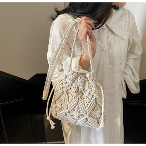 Détail d'un sac seau en macramé fait main avec des motifs tissés et des pompons à franges