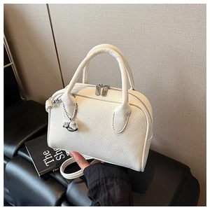 Detailed close-up of white lychee leather texture and dolphin pendant on bowling bag