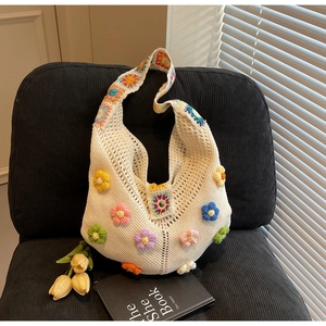 Detail of white handmade crochet hobo bag featuring colorful 3D floral knitting patterns