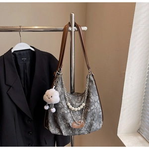 Detail of floral tote bag featuring pearl chain strap and plush cloud pendant accessory