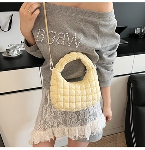 Detail of yellow quilted dumpling bag with soft ruched texture and crossbody strap