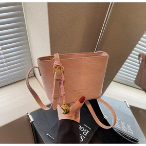 Detail of pink crocodile pattern bucket bag with decorative charm and brand embossing