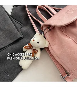 Detail of white plush bear pendant with Love ribbon on pink textured handbag accessory