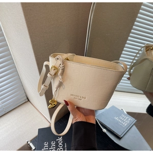Detail of cream bucket bag with crocodile texture and gold heart pendant decoration