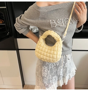 Close-up of quilted puff bag detail with light yellow nylon fabric and smooth stitching