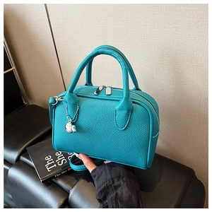 Close-up of turquoise Boston bag with pebble leather texture and silver rabbit charm