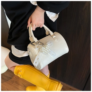 Détail du sac cylindre crème avec texture plissée et accessoire perle et dentelle