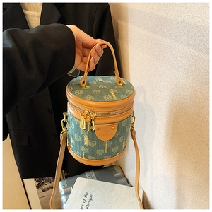 Detail of denim bucket bag with leather trim and monogram print shown in hand