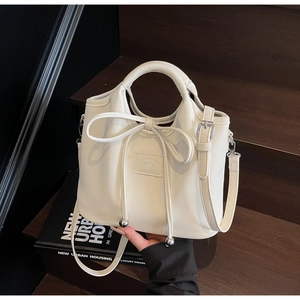 Detail of cream PU leather handbag with elegant bow tie decoration and silver hardware