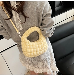 Side view of a light yellow quilted hobo bag styled with a gray sweatshirt and lace skirt