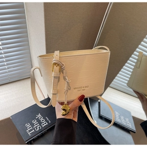 Detail of cream white bucket bag featuring crocodile texture and gold hardware accents