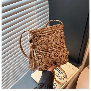 Detail view of handmade straw crossbody bag with floral texture and tassel with wood beads