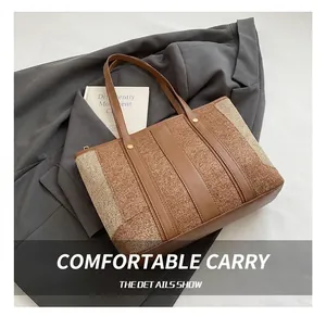 Detail of the leather handle and metal rivet reinforcement on a brown denim tote bag