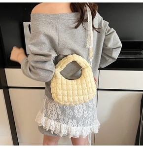 Detail of pale yellow quilted cloud bag featuring soft puffy texture and lace strap detail