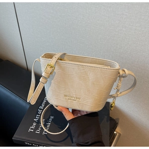 Detailed macro view of cream crocodile-embossed bucket bag with gold-tone hardware