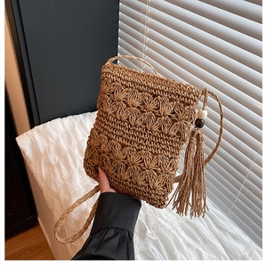 Detail of hand-woven straw bag featuring wavy flower texture and wooden bead tassel