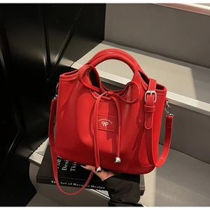 Detail of red drawstring handbag showing metallic logo and elegant bow design texture