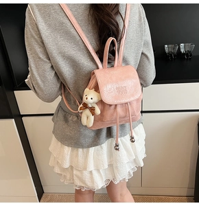 Pink faux leather bucket backpack with drawstring and cute bear charm on a model