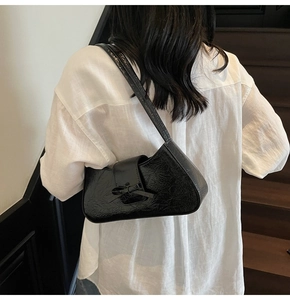 Close-up of black wrinkled leather underarm bag with a decorative bow detail