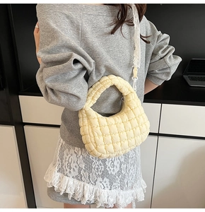 Detail of pale yellow quilted puffer bag with chic lace strap and soft puffy nylon texture
