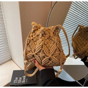 Vue détaillée du sac seau en macramé tressé avec perles en bois et pompons décoratifs