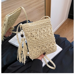 Detail of handmade straw bag with hollow floral texture and wooden bead tassels