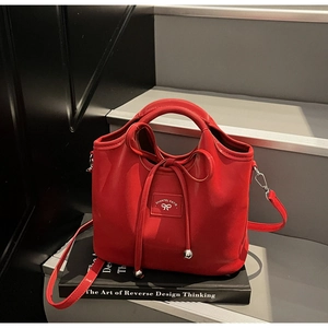 Detailed close-up of a red leather bucket bag with bow detail on a black staircase